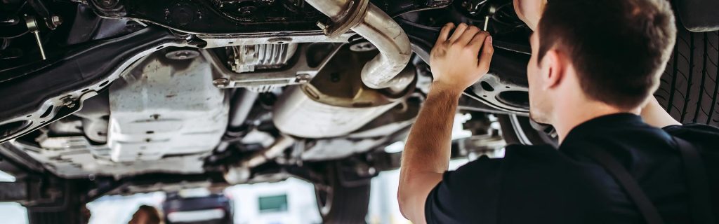 A GMC Service Center certified maintenance specialist makes a GMC SUV engine undercarriage adjustment
