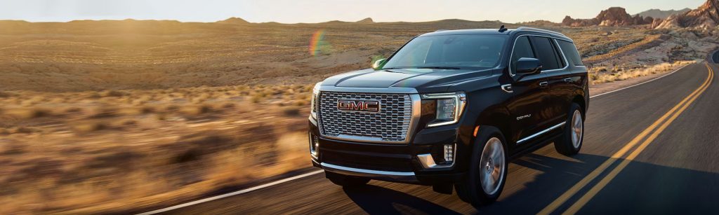 A black GMC SUV is shown being driven on a desert highway
